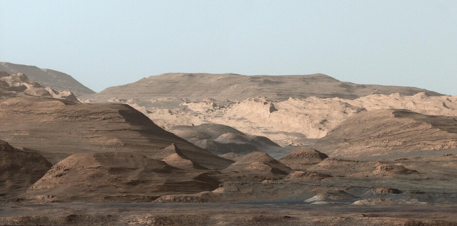 An image taken by the Curiosity Rover MastCam  instrument shows layered sedimentary rocks composing Mount Sharp. The rover has been driving from the floor of Gale crater up through the rocks within these hills in order to understand how the rocks change f